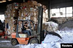FILE - A laborer works at a paper products recycling station in Shanghai, China, Nov. 17, 2017.