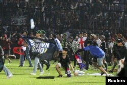 Para suporter Arema FC memasuki lapangan setelah tim mereka kalah dari Persebaya usai pertandingan di Stadion Kanjuruhan, 1 Oktober 2022 (foto: dok).