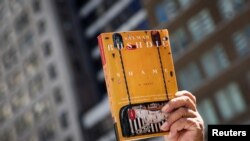 FILE - Seorang pendukung mengangkat salinan buku 'Shame' karya penulis Salman Rushdie saat berlangsungnya aksi solidaritas untuk kebebasan berekspresi di Perpustakaan Umum New York, AS, 19 Agustus 2022. (REUTERS/Brendan McDermid)