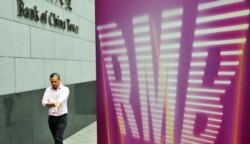A business man walks past a RMB (renminbi) poster outside the Bank of China in Hong Kong on Sept. 5, 2011.
