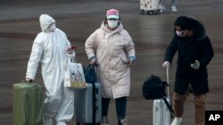 A passenger wearing a full-body protective suit catches the eyes of others as they walk out from the Beijing railway station in Beijing, Feb. 11, 2020. 