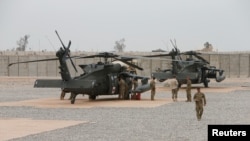 Des soldats américains se tiennent à côté d'hélicoptères à l'aérodrome de Qayyarah en Irak, le 1er mars 2017. 