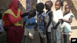 A social worker gives polio drops to children from al-Muniera village in Madani, FILE November 18, 2007. 