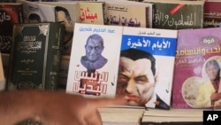 An Egyptian displays books showing cartoons on the covers of former Egyptian President Hosni Mubarak in Cairo, Egypt, May 23, 2011