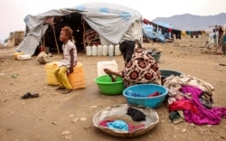 FILE - A woman washes clothes at a make-shift camp for displaced Yemenis who fled fighting between the Houthi rebels and the Saudi-backed government, in the Abs district of the northwestern Hajjah province, Aug. 17, 2019.