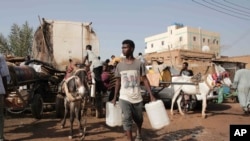 FILE - People gather to collect water in Khartoum, Sudan, May 28, 2023.