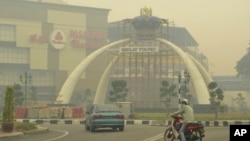 A motorist wears a face mask as he rides through a town shrouded with thick haze in Muar, northwestern Johor, Malaysia, June 22, 2013.
