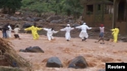 People wearing protective suits hold hands as they cross a river after a mudslide in the mountain town of Regent, Sierra Leone, Aug. 15, 2017, in this still image taken from a video.