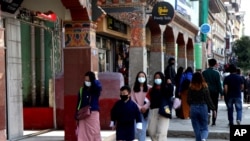 Bhutanese people wearing face masks as precaution against coronavirus walk through a street in Thimpu, Bhutan, Monday, April 12, 2021. The tiny Himalayan kingdom is wedged between India and China.