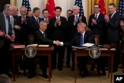 FILE - President Donald Trump and Chinese Vice Premier Liu He shake hands after signing "phase one" of a U.S. - China trade agreement, in the East Room of the White House, Jan. 15, 2020, in Washington.