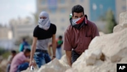 Palestinian demonstrators take cover during clashes with Israeli troops near Ramallah, West Bank, Sept. 29, 2015. 