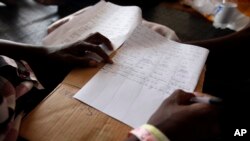 Seorang migran Afrika menuliskan beberapa frasa dalam berbagai bahasa di luar negeri di atas kapal Geo Barents setelah diselamatkan di Laut Mediterania, lepas pantai Libya, Minggu, 26 September 2021. (AP/Ahmed Hatem)