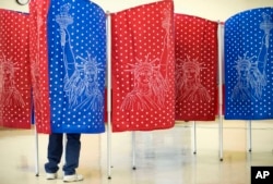 FILE - A voter marks a ballot for the New Hampshire primary inside a voting booth at a polling place, Feb. 9, 2016, in Manchester, N.H.