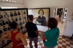 FILE - Visitors view portraits of victims executed by the Khmer Rouge regime, at the Tuol Sleng Genocide Museum in Phnom Penh, Cambodia, April 9, 2015.