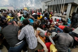 FILE - Residents desperate for a planned distribution of food for those suffering under Kenya's coronavirus-related movement restrictions push through a gate and create a stampede, at a district office in the Kibera slum of Nairobi.
