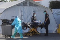 FILE - An ambulance crew waits with a patient outside the Coast Plaza Hospital emergency room during a surge of coronavirus disease (COVID-19) cases in Los Angeles, California, Dec. 26, 2020.