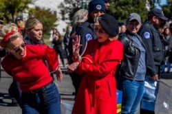 Actress Jane Fonda, center, gives fellow activist a high five after they were arrested during a rally on Capitol Hill in Washington, Oct. 18, 2019.