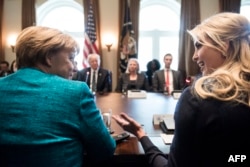 Germany's Chancellor Angela Merkel (L) and Ivanka Trump (R) talk before a meeting with US President Donald Trump and business leaders in the Cabinet Room of the White House, March 17, 2017 in Washington, D.C.