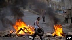 Palestinians burn tires during Israeli military raid in the West Bank city of Nablus, Oct. 6, 2015. 