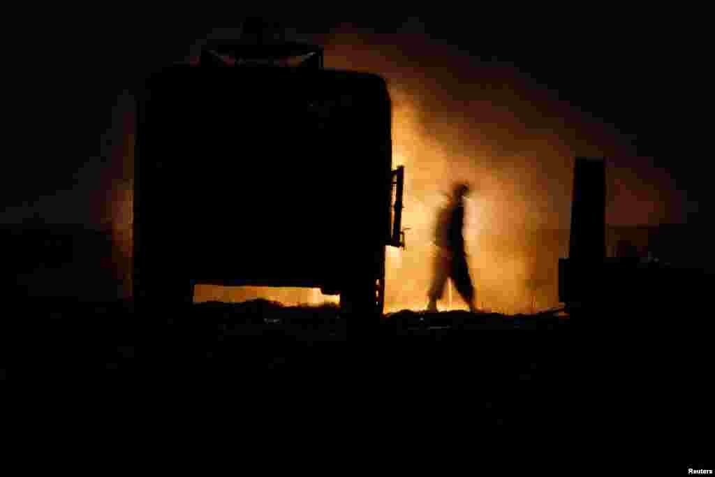Un soldado israelí camina junto a un vehículo militar en la ubicación de una unidad de artillería móvil en el lado israelí por la frontera de Israel con Gaza. 