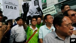 Protesters raise a mock "white paper", left, released by Beijing State Council on Tuesday saying it holds ultimate control over the former British colony, outside the Chinese liaison office in Hong Kong, June 11, 2014. 