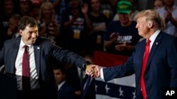 FILE - Troy Balderson, left, reaches for President Donald Trump as he speaks at a rally at Olentangy Orange High School in Lewis Center, Ohio, Aug. 4, 2018. 