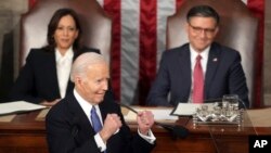 ভাষণের মাঝে প্রেসিডেন্ট জো বাইডেন । পেছনে (বাঁয়ে) ভাইস প্রেসিডেন্ট কামালা হ্যারিস এবং স্পিকার মাইক জন্সন। 