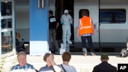 FILE - People wait for a train in the foreground as members of a police forensics team take part in an investigation next to a Thalys train on the platform at Arras train station, northern France, Aug. 22, 2015. 