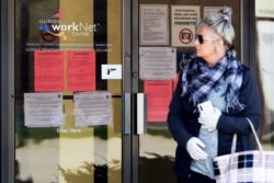 A woman looks to get information about job application in front of IDES (Illinois Department of Employment Security) WorkNet center in Arlington Heights, Ill., April 9, 2020.