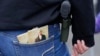 FILE - A woman wears a gun in a holster next to two copies of the U.S. Constitution during a gun rights rally at the Capitol in Olympia, Wash.