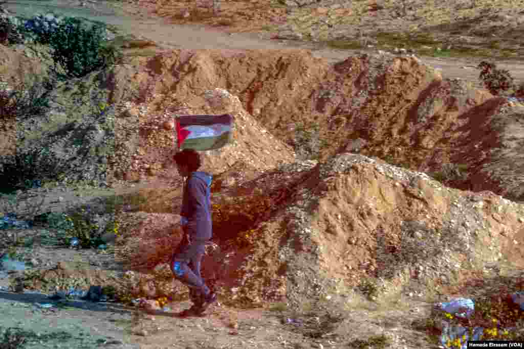 An Egyptian child carries the Palestinian flag down a rocky road near the Rafah border, less than 2 kilometers away from the decimated Gaza Strip following 16 months of Israeli bombardments. Rafah, Egypt, Feb. 4, 2025.