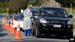 Medical staff prepare take a COVID-19 test from a visitor to a drive through community based assessment center in Christchurch, New Zealand, Aug. 13, 2020.
