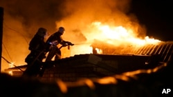 Lính cứu hỏa dập lửa tại một ngôi nhà bị trận pháo kích kéo dài suốt đêm phá hủy ở Donetsk, 16/8/2015.