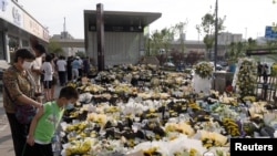 People stand next to flowers placed at an entrance to a subway station of Metro Line 5 in memory of flood victims following heavy rainfall in Zhengzhou, Henan province, on July 27, 2021. (Source: China Daily via Reuters) 