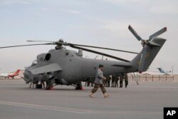FILE - An Afghan soldier walks past Indian-donated helicopters to Afghanistan at the Kabul airport in Kabul, Afghanistan, Dec. 25, 2015.