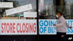 A man looks at signs of a closed store due to COVID-19 in Niles, Ill, May 21, 2020. U.S. businesses shed 2.76 million jobs in May, as the economic damage from the historically unrivaled coronavirus outbreak stretched into a third month.