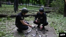 Ukrainian police officers examine fragments of a missile in the central park of Kharkiv on May 19, 2024, amid the Russian invasion in Ukraine.
