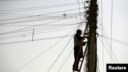 FILE - An Afghan man repairs electricity cables along the streets of Kabul, Nov. 16, 2009. The country is negotiating for an increase in energy supplies from its Central Asian neighbors.