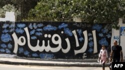 A Palestinian man and his daughter walk past a graffiti reading in Arabic ''Division'' in Gaza City, on Sept. 17, 2017, after Hamas announced it had agreed to steps toward resolving a decade-long split with the Fatah movement.