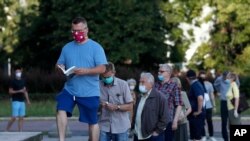 People, practicing social distancing, wait in line to cast their vote in presidential elections, in Warsaw, Poland, June 28, 2020. 