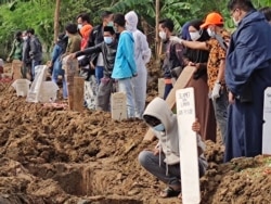 Relatives attend funerals of family members who died from the coronavirus at a cemetery for COVID-19 victims in TPU Rorotan, north Jakarta, Indonesia, July 8, 2021. (Indra Yoga/VOA Indonesian)