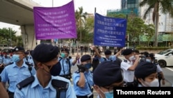 Police officers raise signs warning protesters outside West Kowloon Magistrates' Courts in Hong Kong, March 1, 2021.