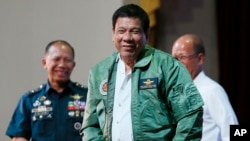 Philippine President Rodrigo Duterte, center, smiles as he is presented with a pilot's jacket during his "Talk with the Airmen" on the anniversary of the 250th Presidential Airlift Wing Tuesday, Sept. 13, 2016 at the Philippine Air Force headquarters in suburban Pasay city, southeast of Manila, Philippines. On Monday, President Duterte, in his first public statement opposing the presence of American troops, said he wants U.S. forces out of his country's south and blamed the United States for inflaming Muslim insurgencies in the region.