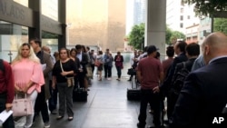 FILE - Immigrants awaiting deportation hearings line up outside the building that houses the immigration courts in Los Angeles, June 19, 2018.