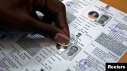 An election staff member pastes a hologram on a voter identification card at an election branch of a district administrative office in the western Indian city of Ahmedabad, April 4, 2014. 