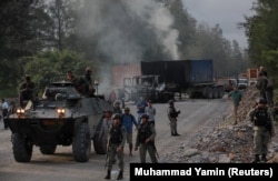 Polisi dan pasukan keamanan terlihat di dekat kendaraan yang dibakar oleh para pekerja perusahaan pertambangan raksasa A.S. Freeport McMoran Inc selama perselisihan perburuhan di Timika, Papua, 19 Agustus 2017. (Foto: REUTERS/Muhammad Yamin)