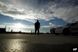 A Harris County Sheriff officer stands at a roadblock along Interstate 45 as rainclouds give way to sunshine after the passing of Tropical Storm Harvey, Aug. 29, 2017, in Houston.