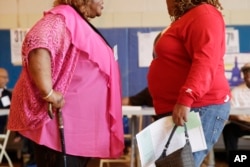 FILE: In this June 26, 2012, photo, two overweight women hold a conversation in New York.