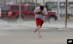 Eli White covers his face from the blowing sand in Nags Head, N.C., as the tail of Tropical Storm Hermine passes the Outer Banks, Sept. 3, 2016.