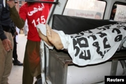 FILE - Ambulance workers load the body of Mashal Khan into an ambulance after a mob beat him to death at his university campus in Mardan, Pakistan, April 13, 2017.